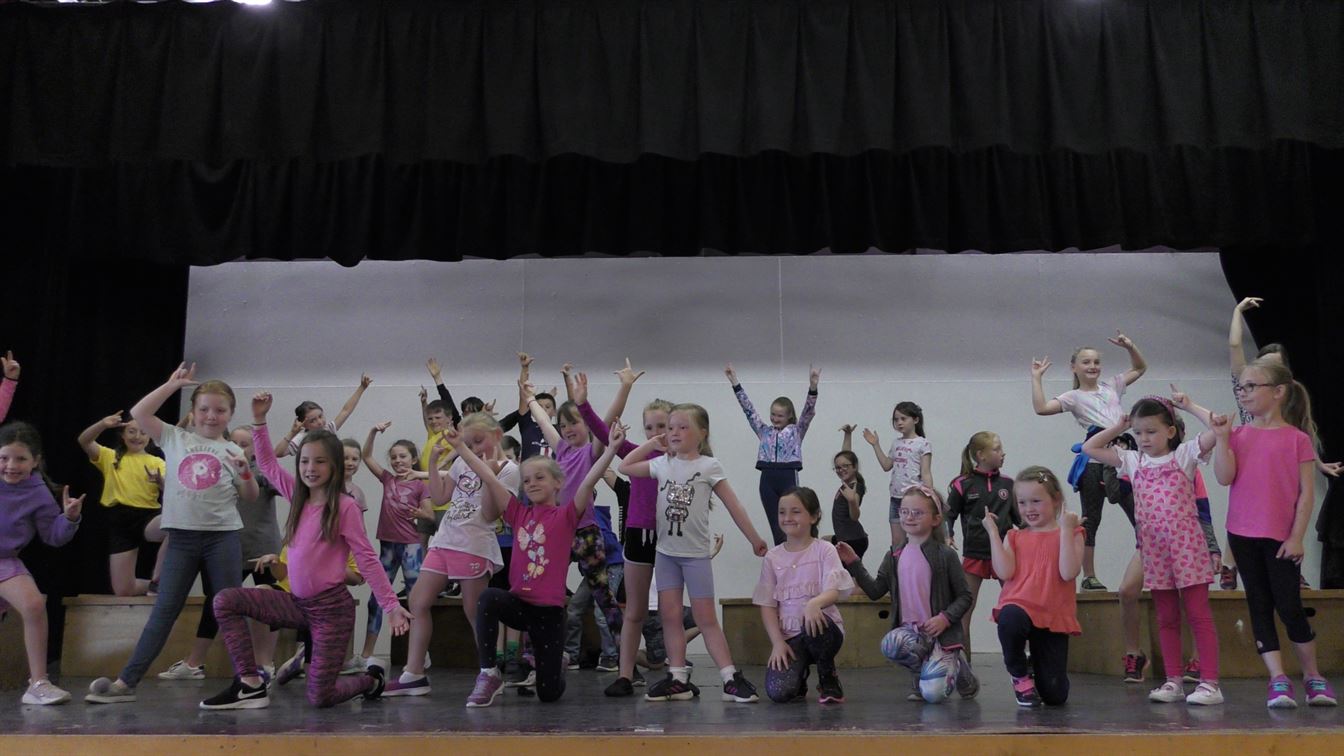 Children dancing on stage at a Hazel Wand summer scheme